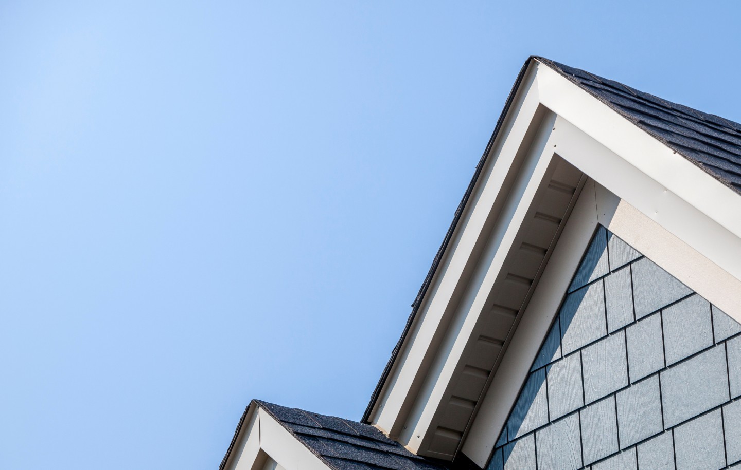 Détail de toiture et bardage d’une maison moderne sous un ciel bleu dégagé